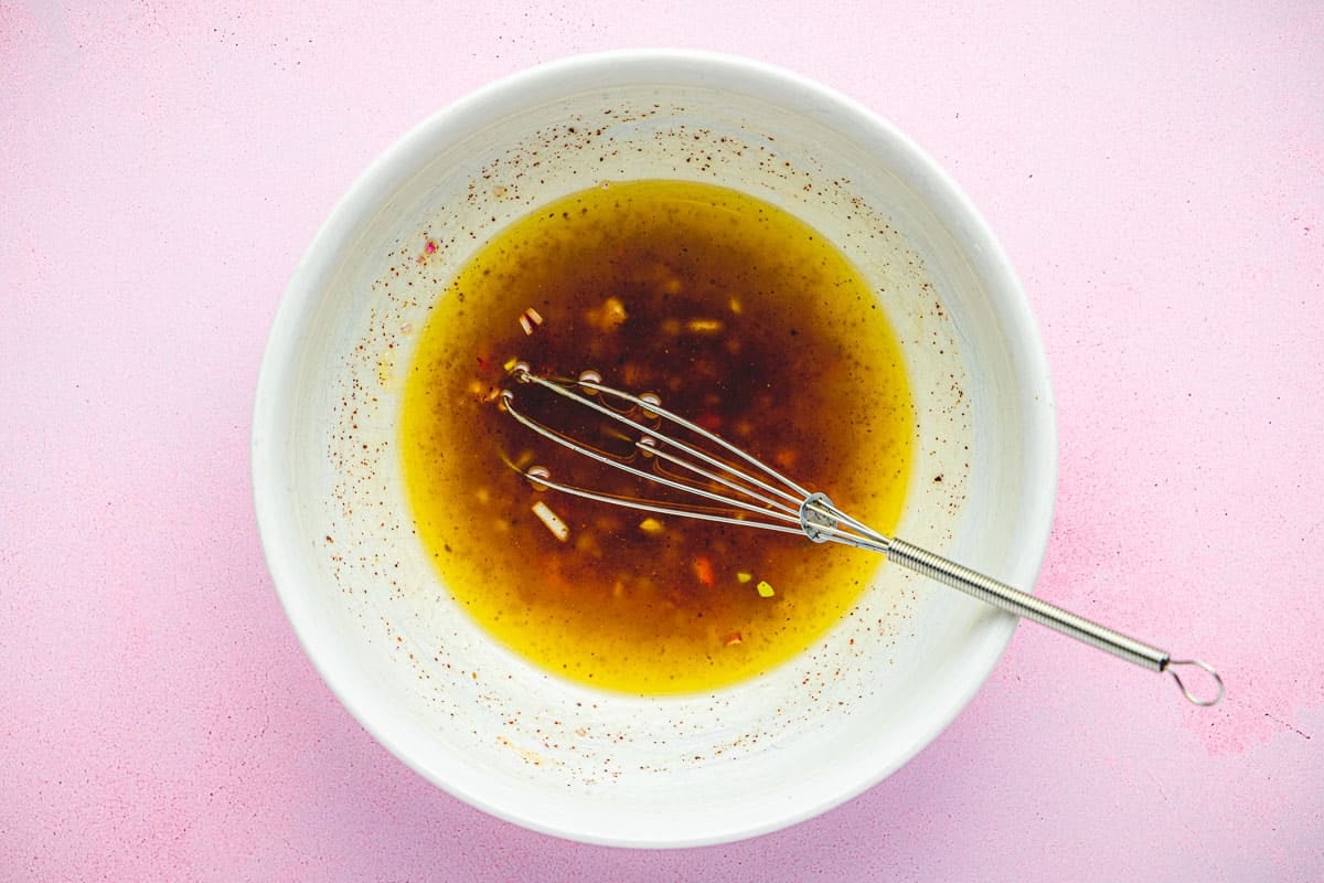 the dressing for the cucumber and radish salad in a bowl with a whisk.