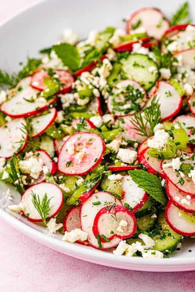 close up of cucumber and radish salad in a bowl.