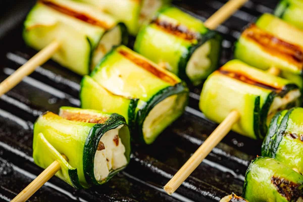 close up of zucchini roll up skewers on a cast iron grill pan.