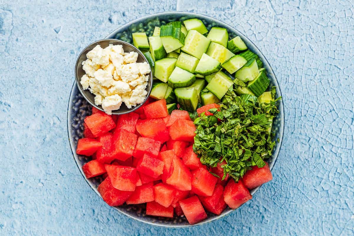 chopped cucumber, cubed watermelon, crumbled feta and shopped mint in a bowl.