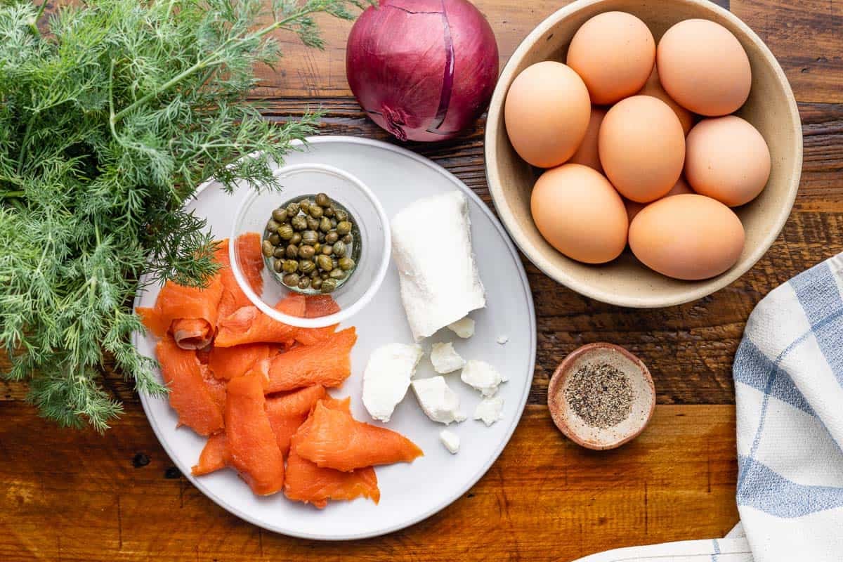 ingredients for egg white frittata including eggs, red onion, dill, smoked salmon, goat cheese, capers, and black pepper.