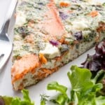 a slice of egg white frittata on a plate with a small salad and a fork.