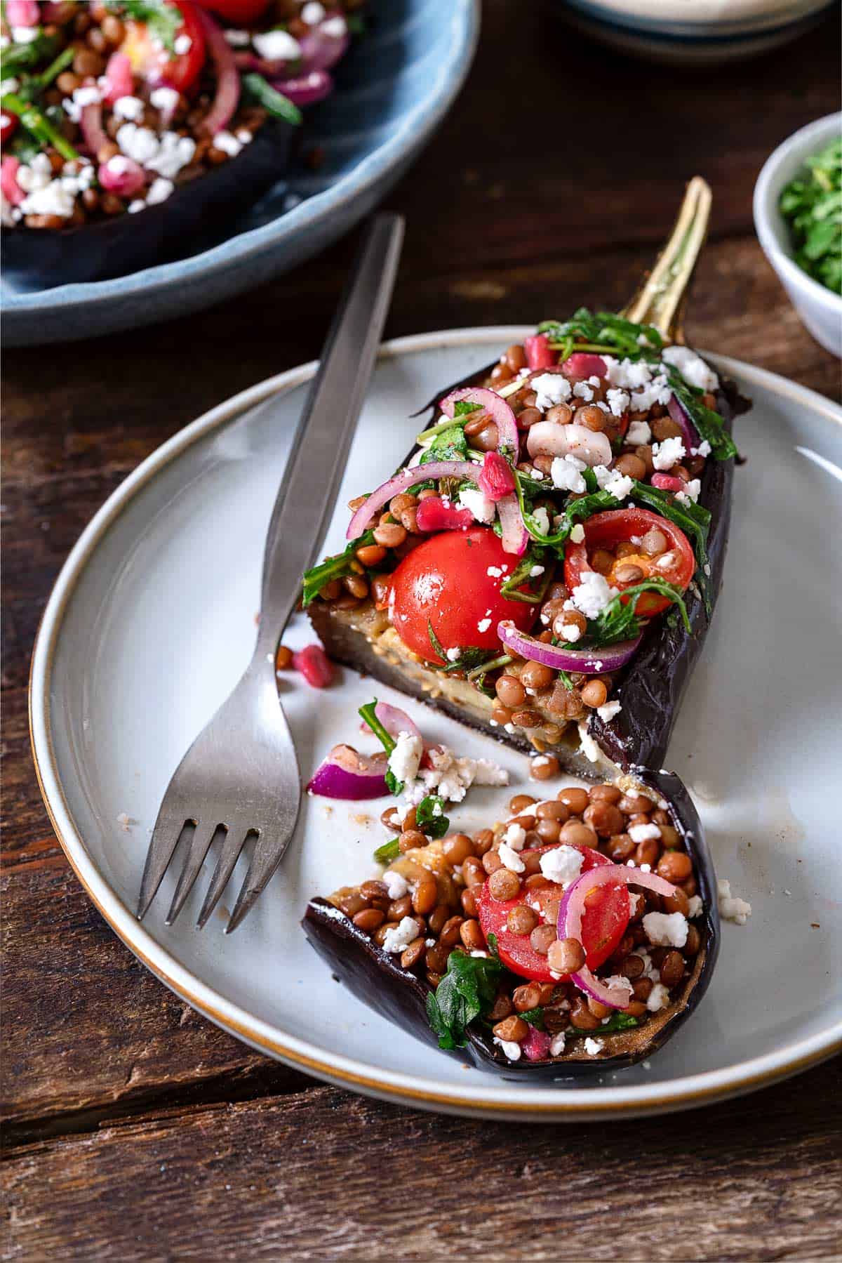 Eggplant salad on a white plate with a fork and a slice going down the middle.