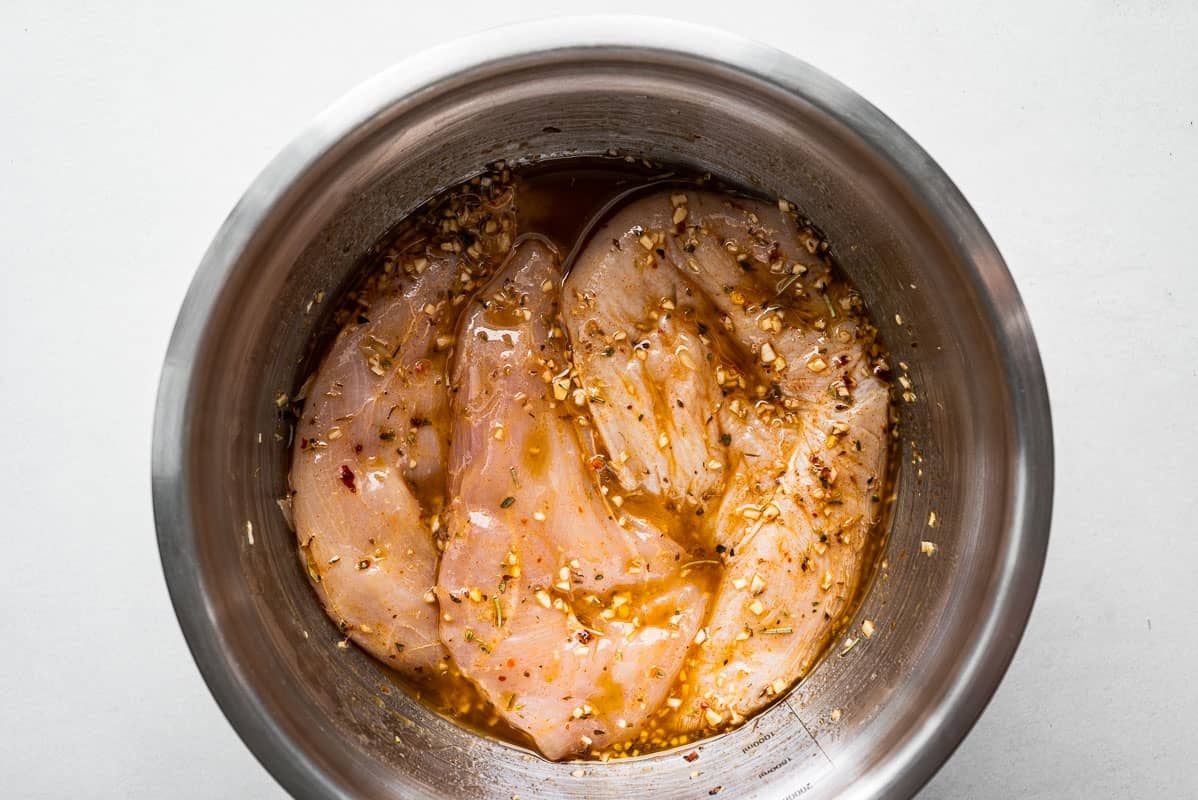 raw chicken breasts marinading in a bowl.