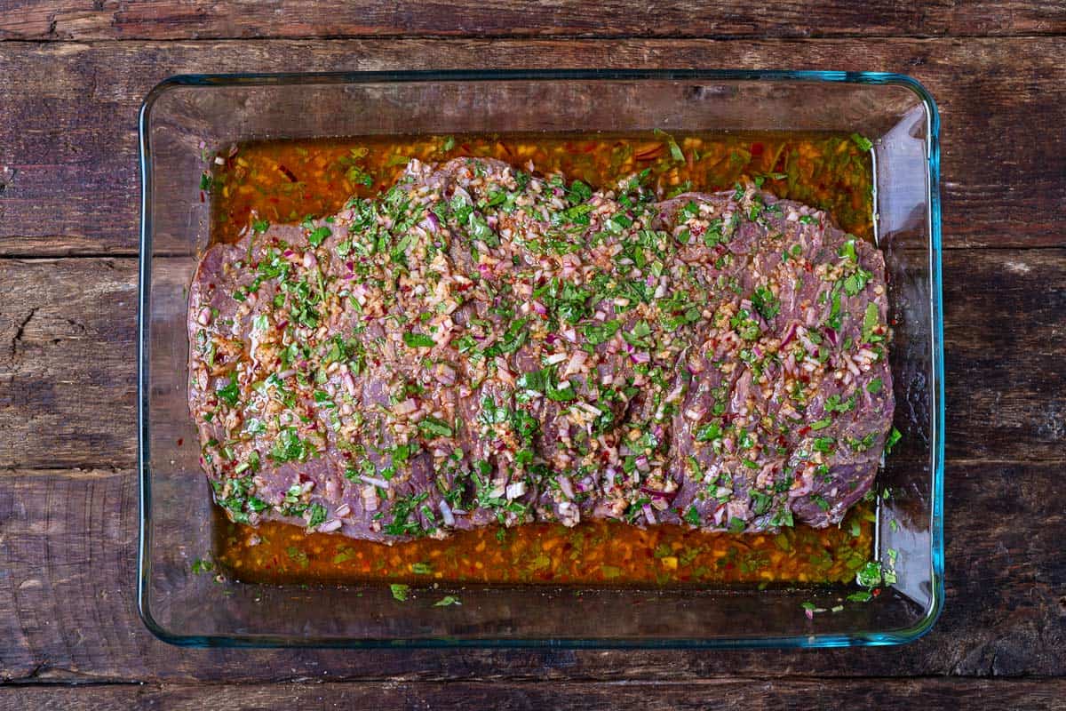 skirt steak marinading in a baking dish.