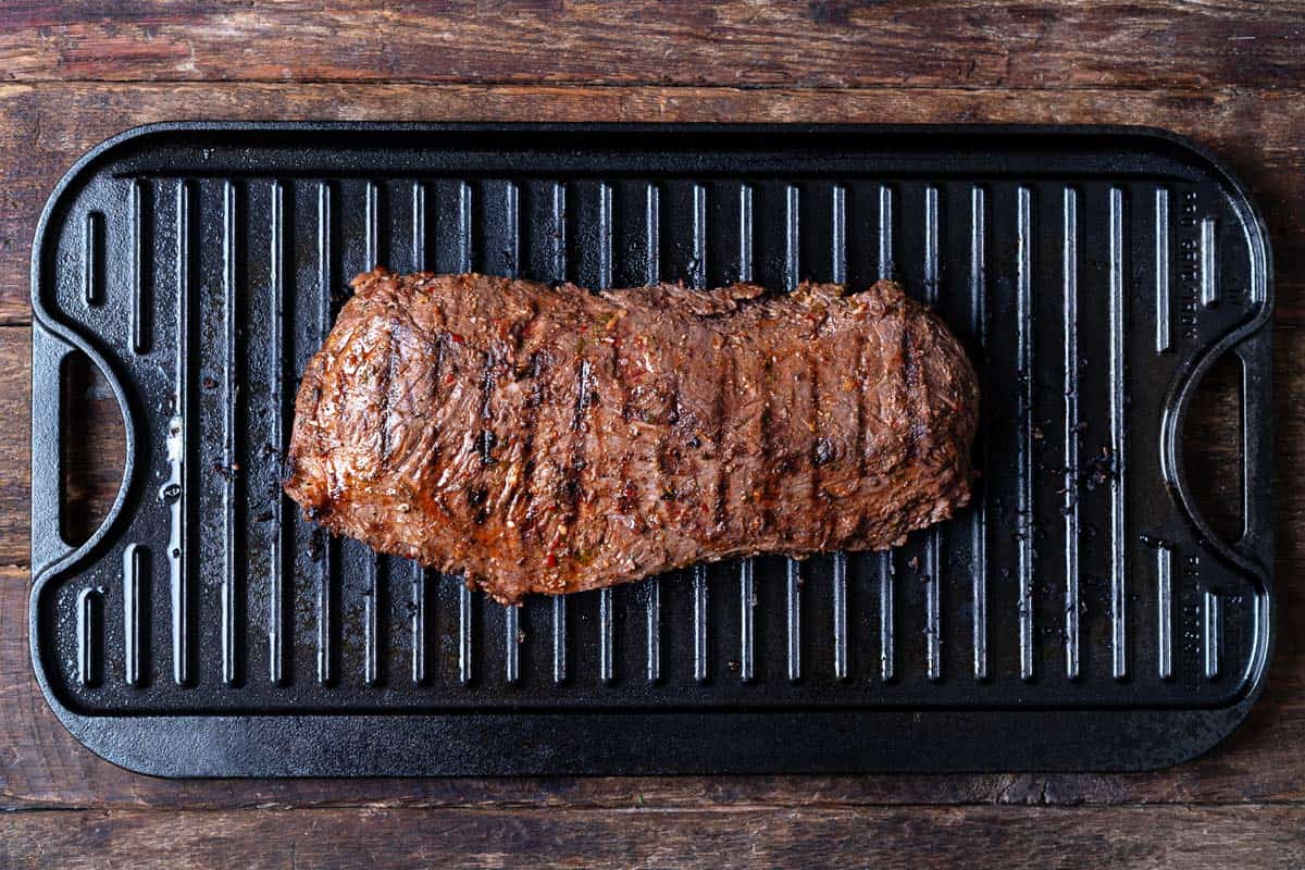 a grilled skirt steak on a cast iron grill pan.