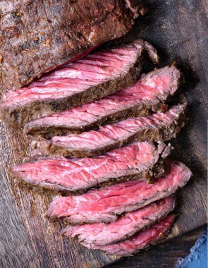 a sliced grilled skirt steak on a wooden cutting board.