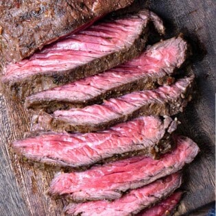 a sliced grilled skirt steak on a wooden cutting board.