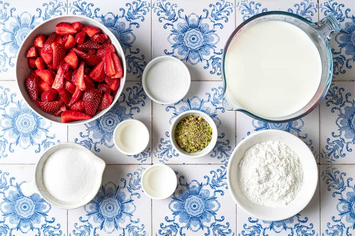 ingredients for Mahalabia (Milk Pudding) including milk, heavy whipping cream, sugar, cornstarch, rosewater, pistachios and quartered strawberries.