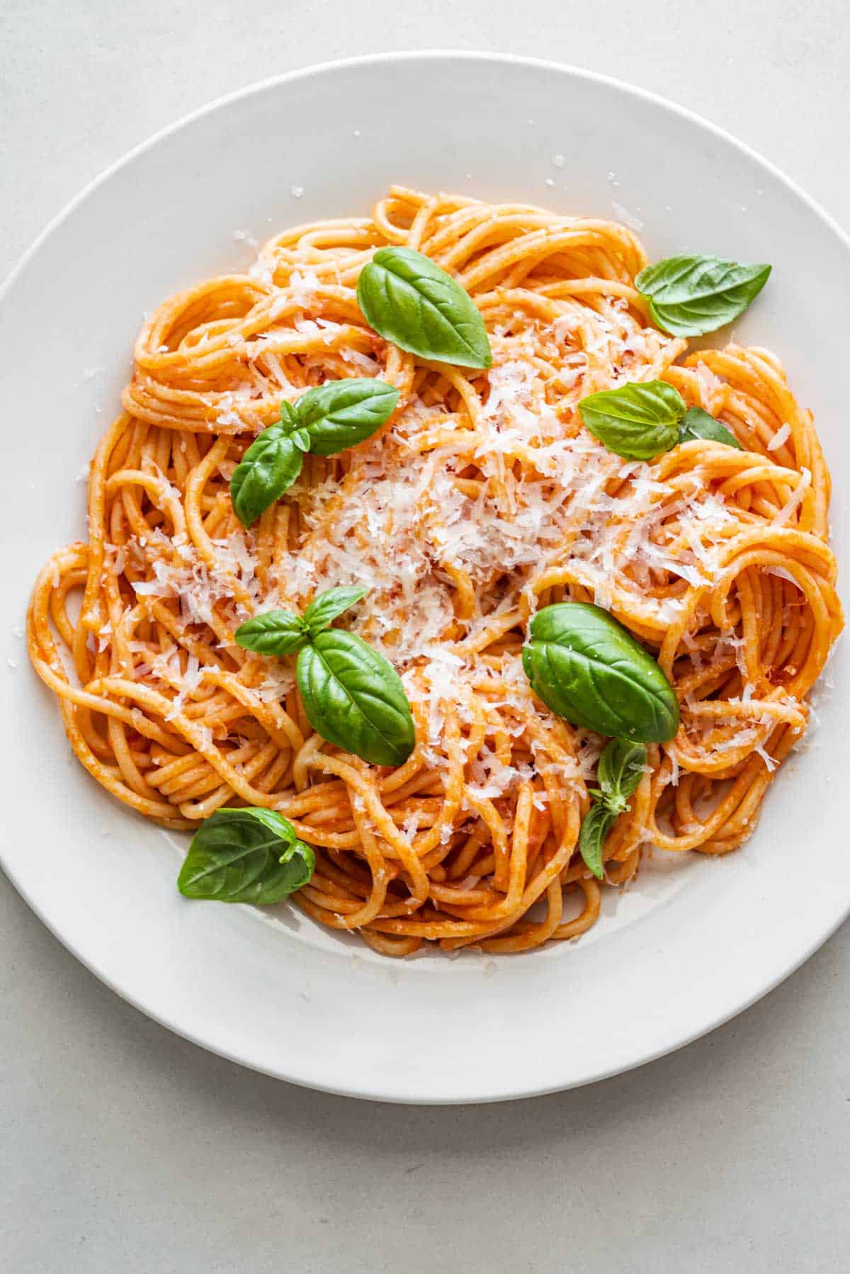 one plate of pasta pomodoro topped with grated parmesan and basil.