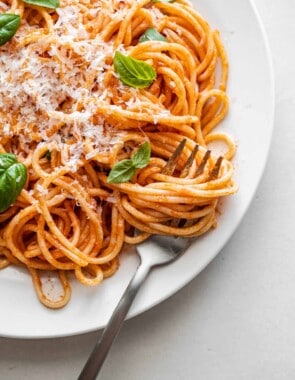 one plate of pasta pomodoro topped with grated parmesan and basil with a fork.