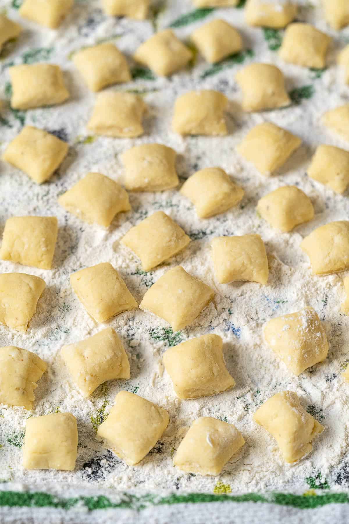 ricotta gnocchi pieces on a towel sprinkled with flour.