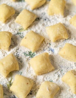 a close up of ricotta gnocchi pieces on a towel sprinkled with flour.