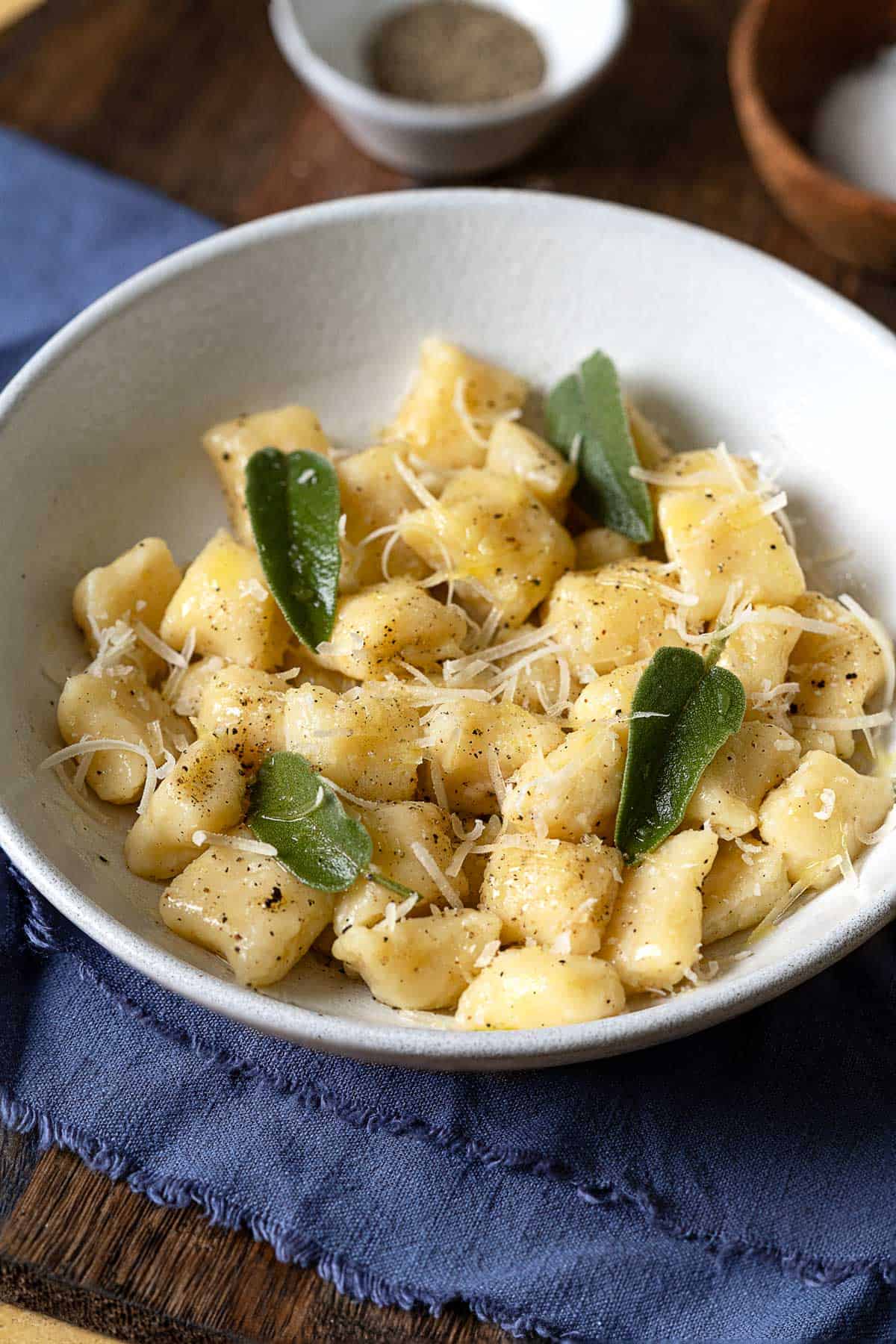 a bowl of cooked ricotta gnocchi toped with a sprinkle of parmesan and fresh basil.