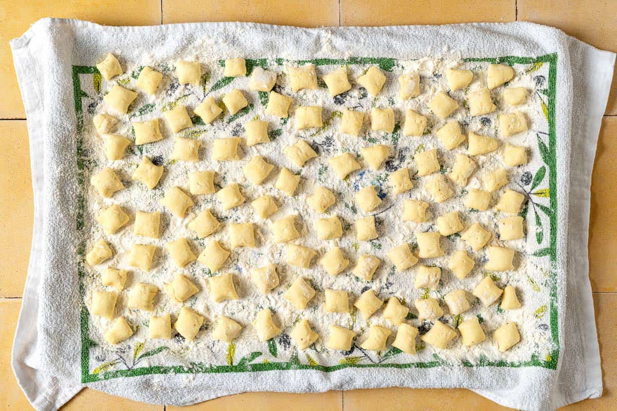 overhead photo of ricotta gnocchi pieces on a towel sprinkled with flour.