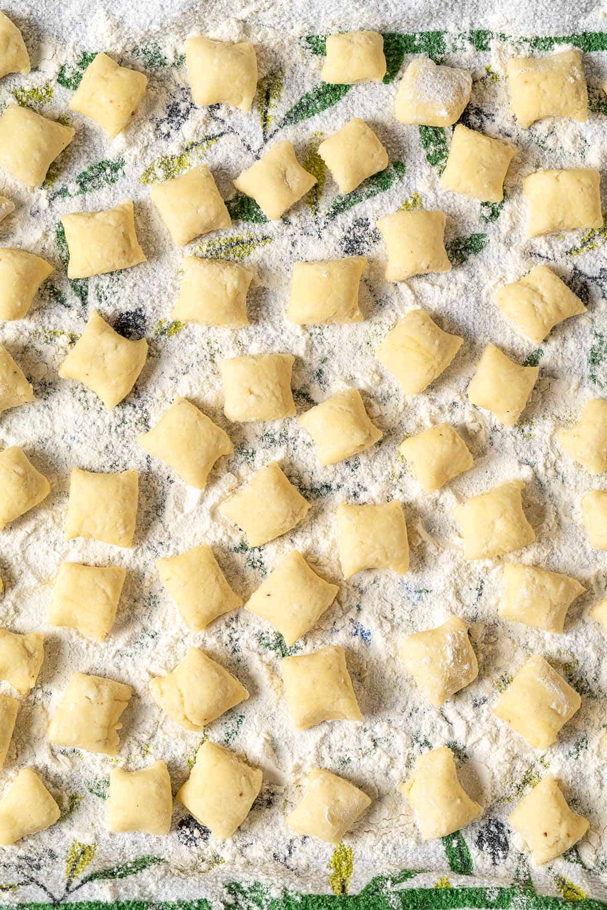 overhead photo of ricotta gnocchi pieces on a towel sprinkled with flour.