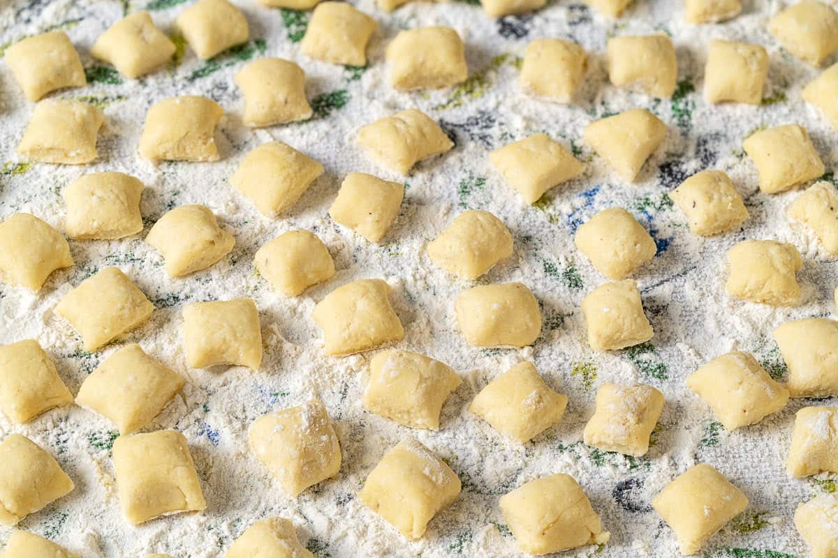 ricotta gnocchi pieces on a towel sprinkled with flour.