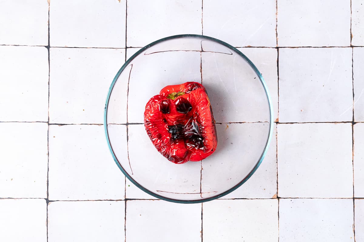 One charred, roasted red pepper in a bowl.