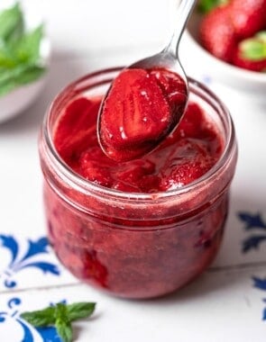 a spoonful of strawberry compote being lifted from a jar of strawberry compote.