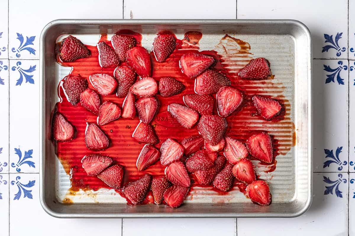 strawberry halves and their juices evenly distributed on a baking sheet.