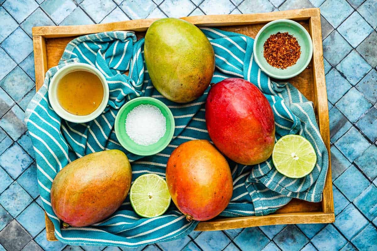 ingredients for grilled mangos including mangos, lime, honey, kosher salt, and aleppo pepper.