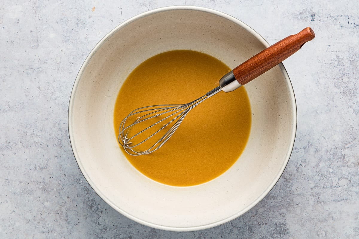 nicoise salad dressing in a bowl with a whisk.