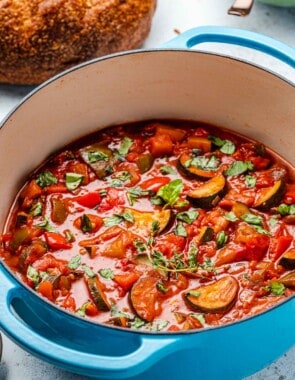 cooked ratatouille in a pot next to a round loaf of bread.