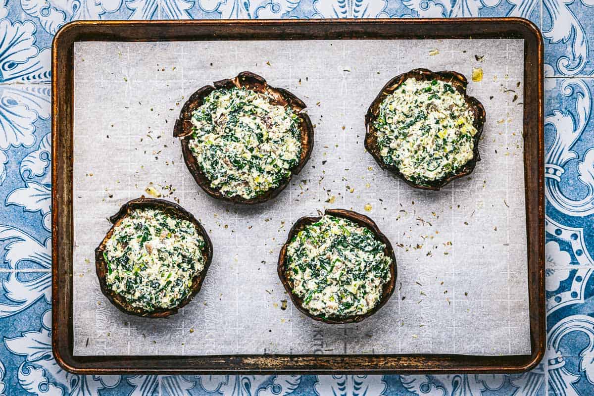 portobello mushroom caps stuffed with the ricotta cheese and sauteed vegetable mixture on a parchment lined baking sheet.