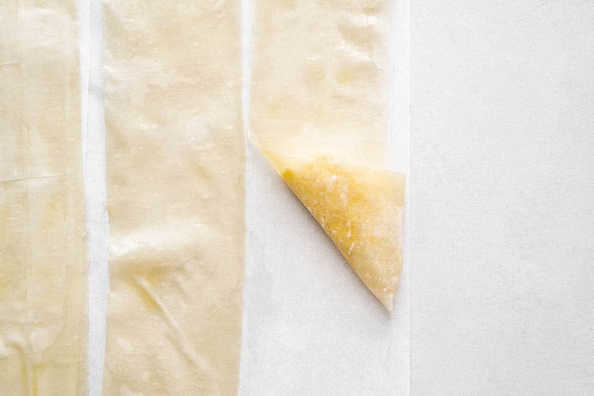 three strips of filo dough on parchment paper.