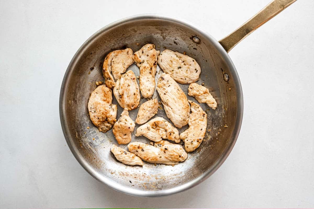 sliced chicken breast being browned in a skillet.