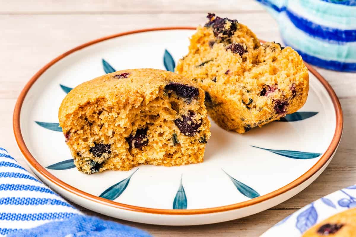 a blueberry muffin split in half on a plate.