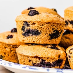 a several blueberry muffins stacked on a plate.