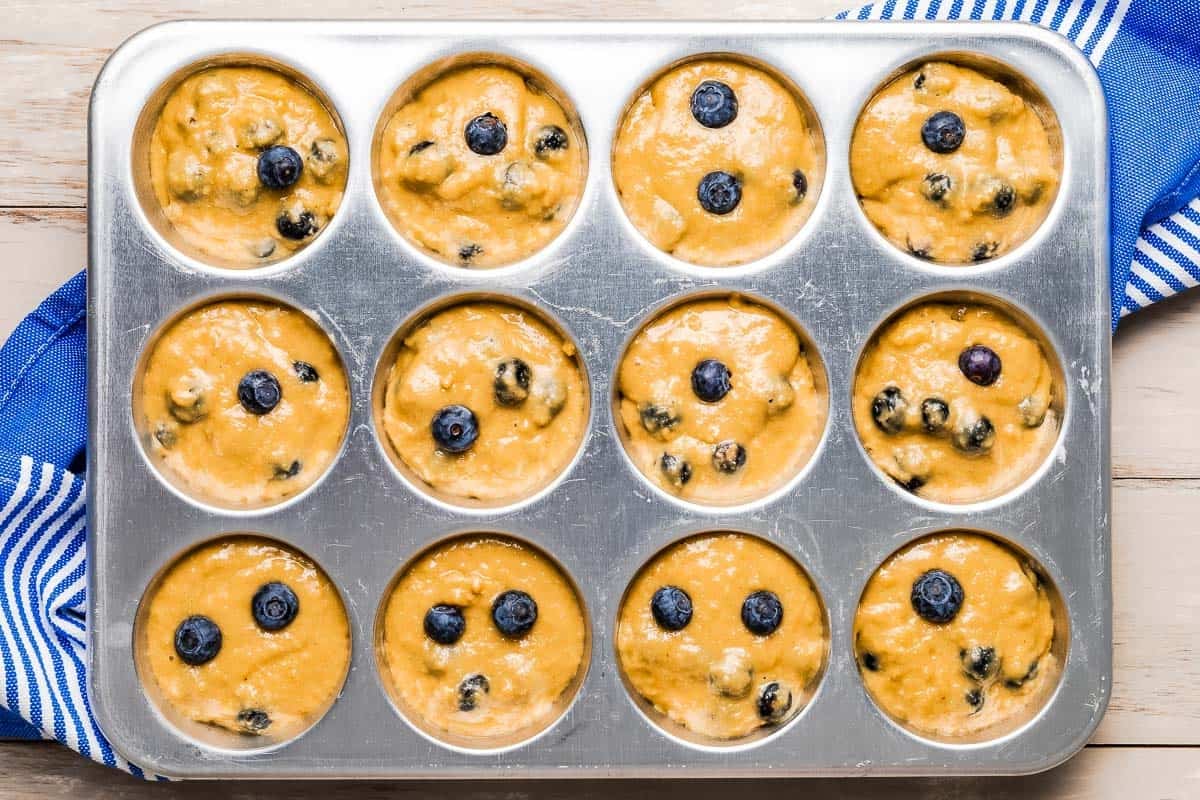 healthy blueberry muffin batter in a muffin tin.