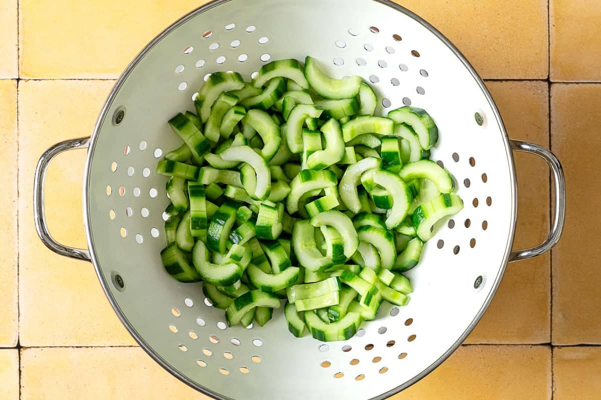 cucumber slices resting in a colander.