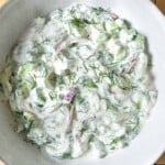 overhead photo of a creamy cucumber salad in a serving bowl.