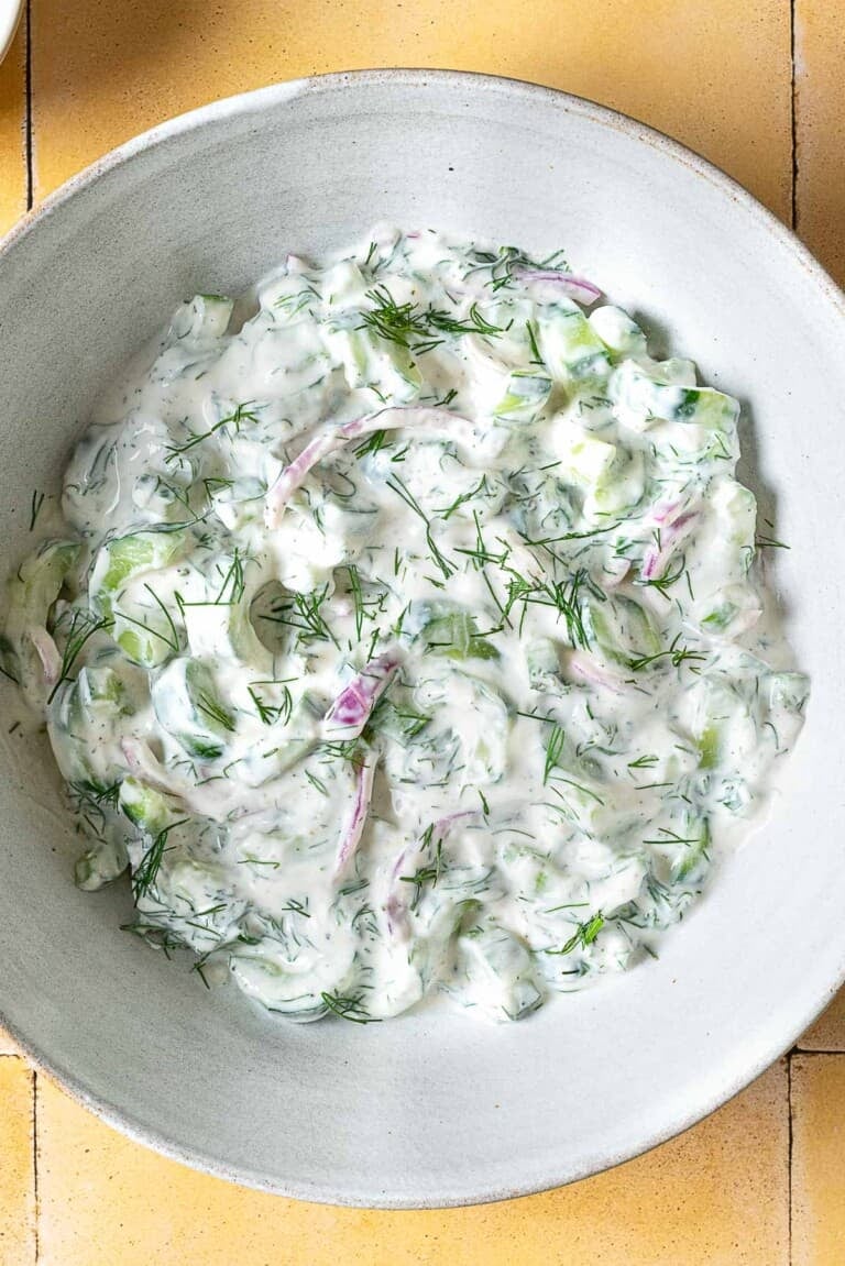 overhead photo of a creamy cucumber salad in a serving bowl.