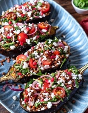 Eggplant salad with four eggplant halves stuffed with lentils, fresh vegetables, arugula, and feta cheese.