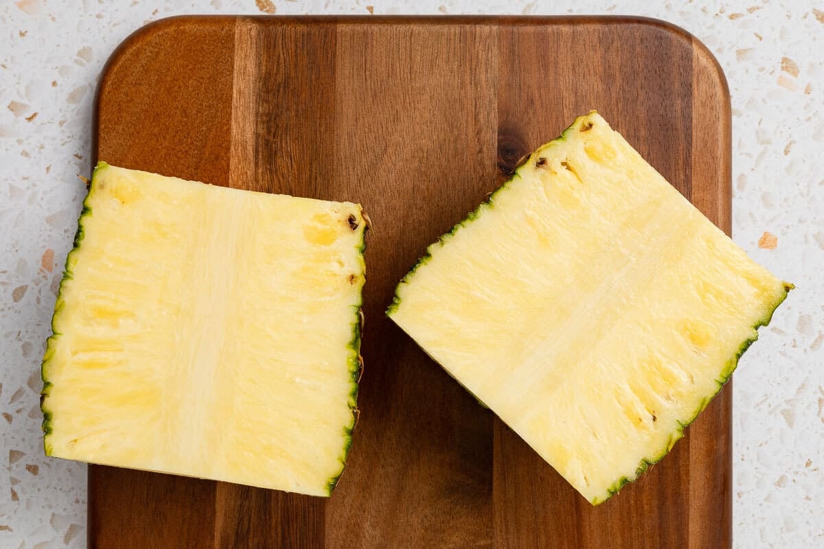 Trimmed pineapple sliced in half.
