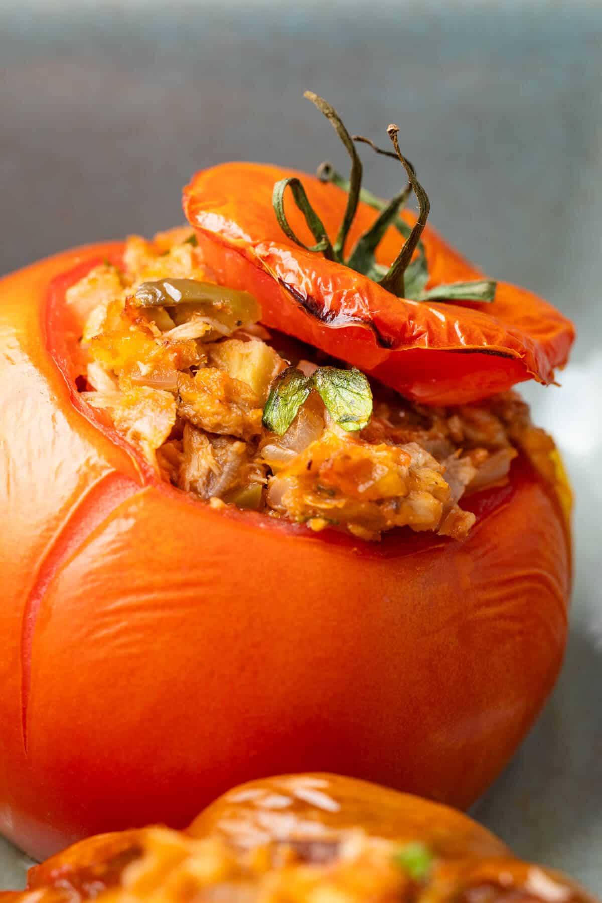 close up of 1 baked stuffed tomato with tuna.