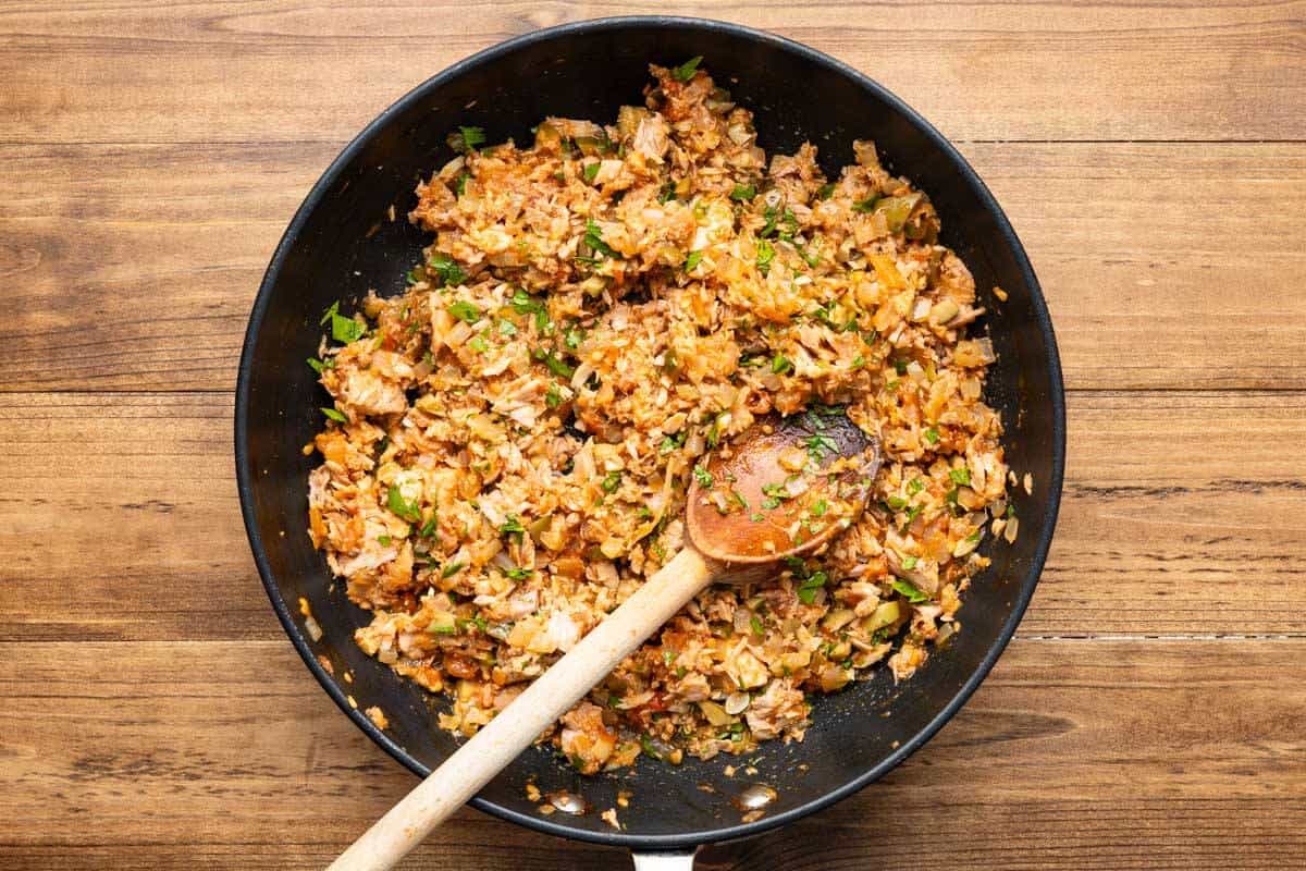 tuna filling for the hollowed out tomatoes in a skillet with a wooden spoon