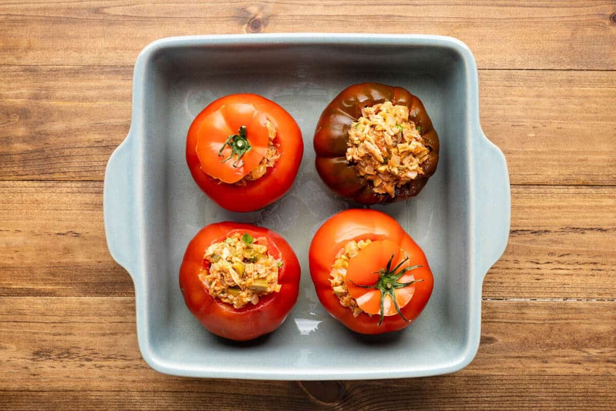 4 baked stuffed tomatoes with tuna in a square baking dish.