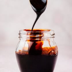 balsamic glaze being drizzled from a spoon into a jar.