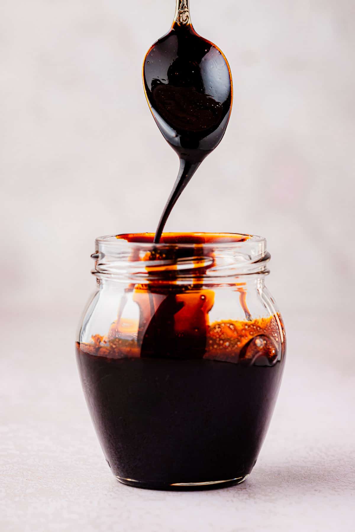 balsamic glaze being drizzled from a spoon into a jar.