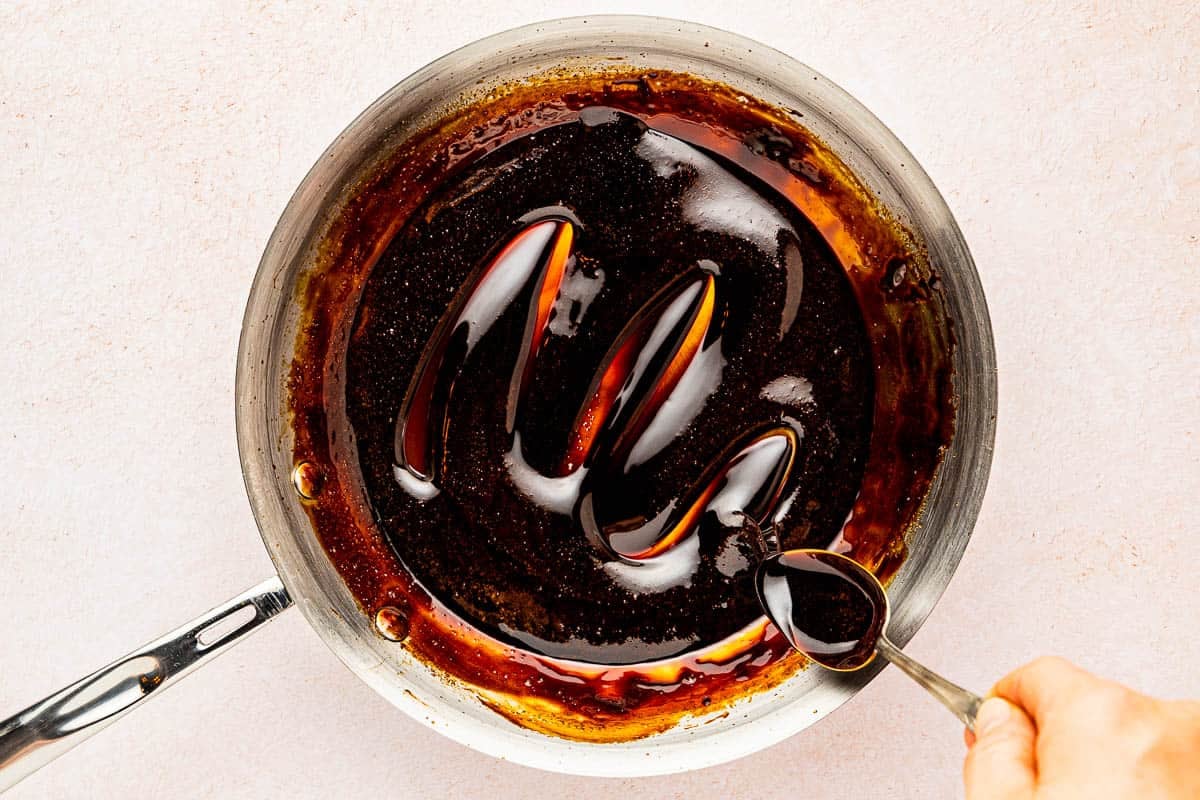 balsamic glaze being stirred with a spoon in a skillet.