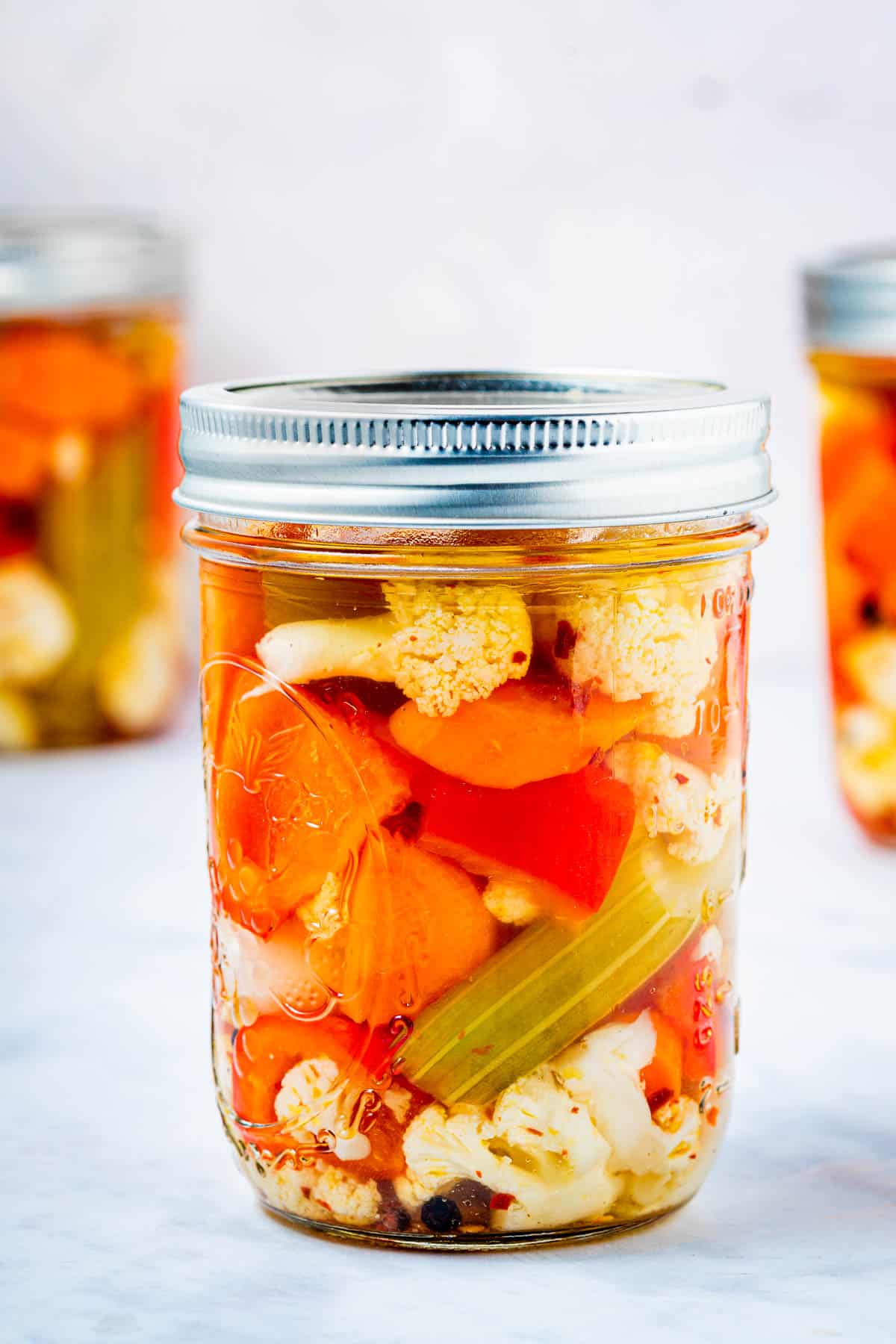 close up of a jar of giardiniera italian pickled vegetables with a lid.