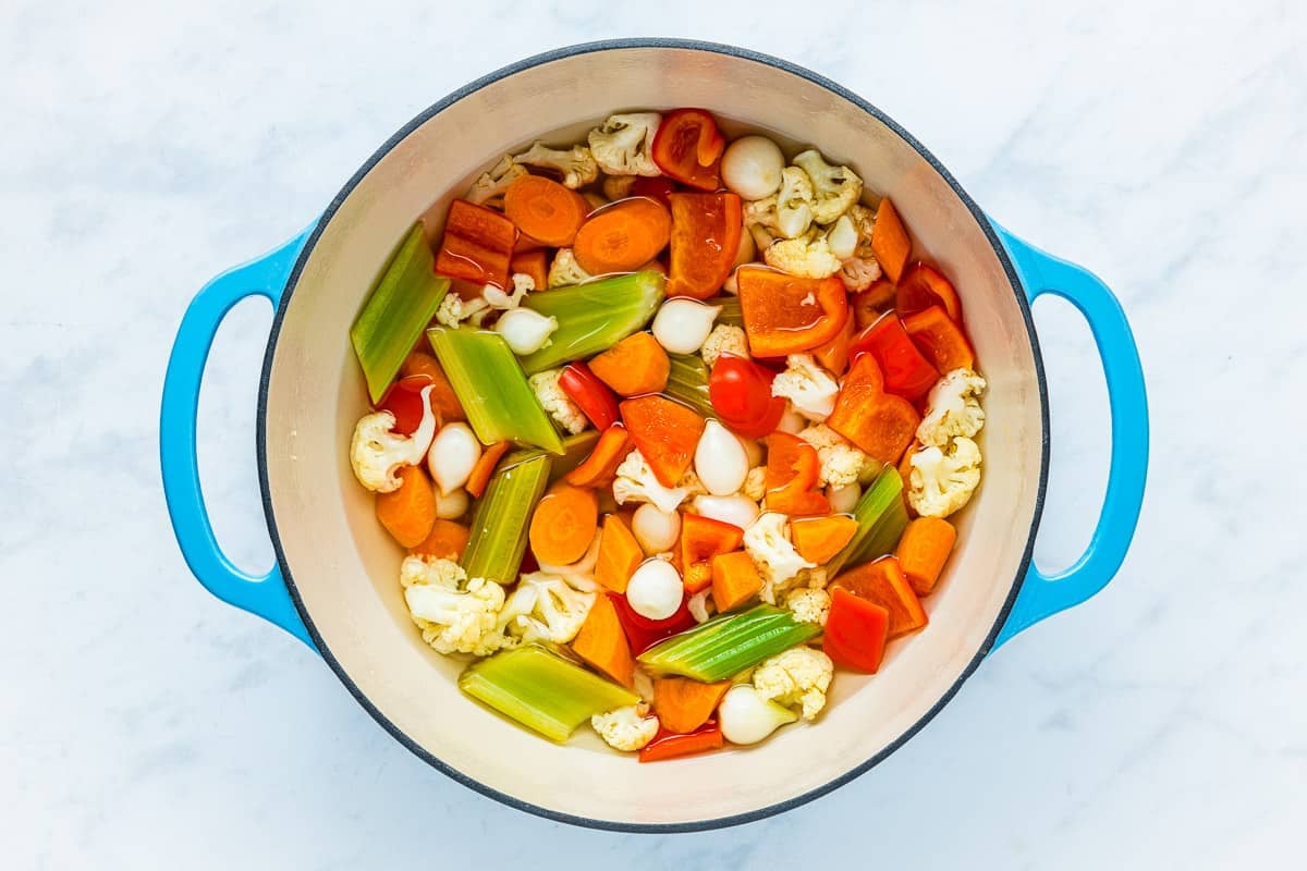 cauliflower, carrot, celery, pearl onion and red bell pepper pieces in a pot of the pickling liquid.
