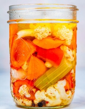 close up of a giardiniera italian pickled vegetables in an open jar.