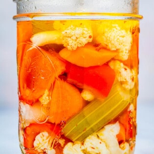 close up of a giardiniera italian pickled vegetables in an open jar.