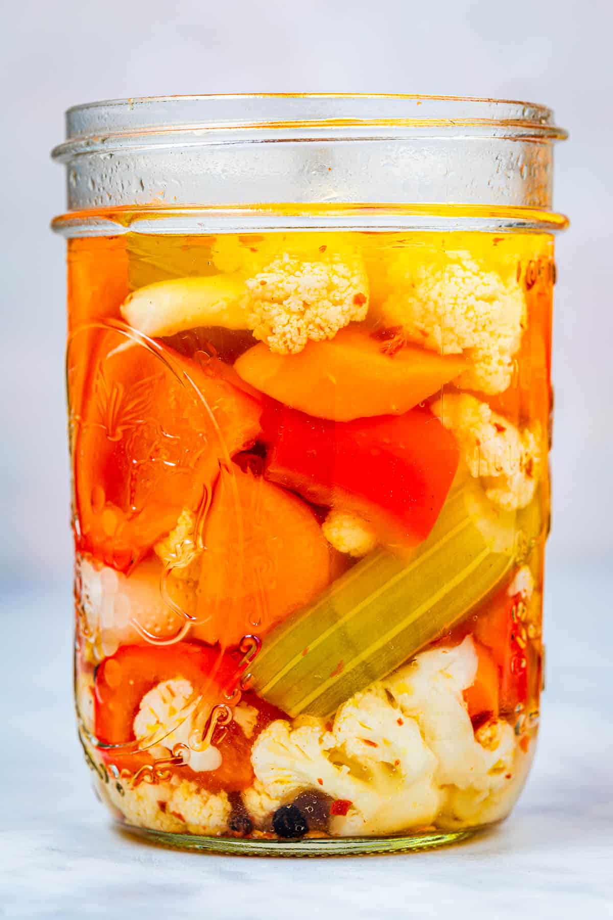 close up of a giardiniera italian pickled vegetables in an open jar.