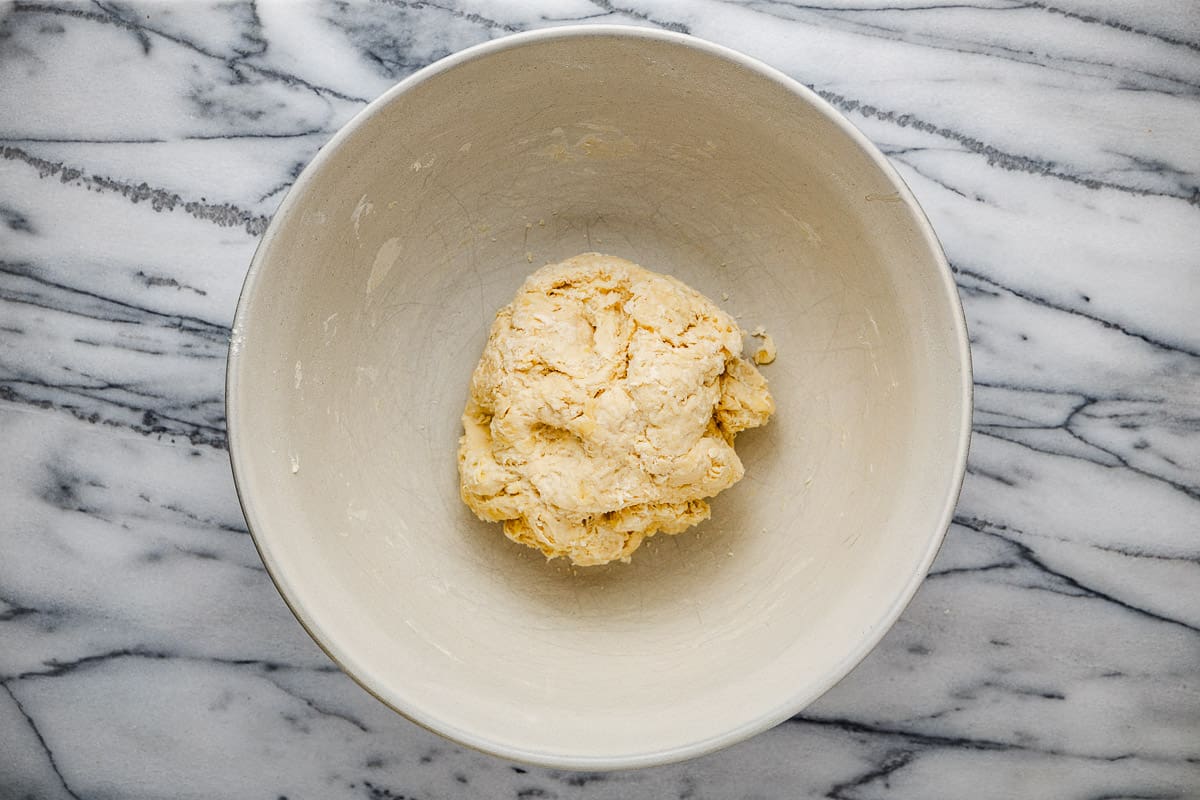 a rough ball of dough in a white mixing bowl.